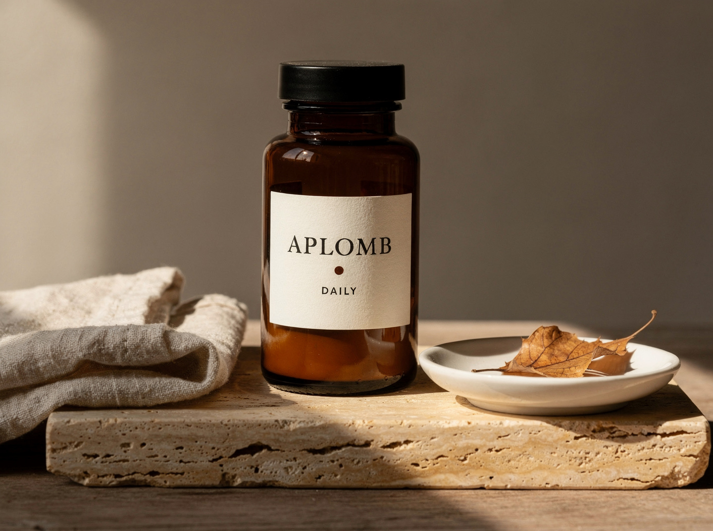 APLOMB. Daily — amber-glass apothecary jar with a cream paper label reading 'APLOMB · DAILY' on a travertine slab in warm window light.