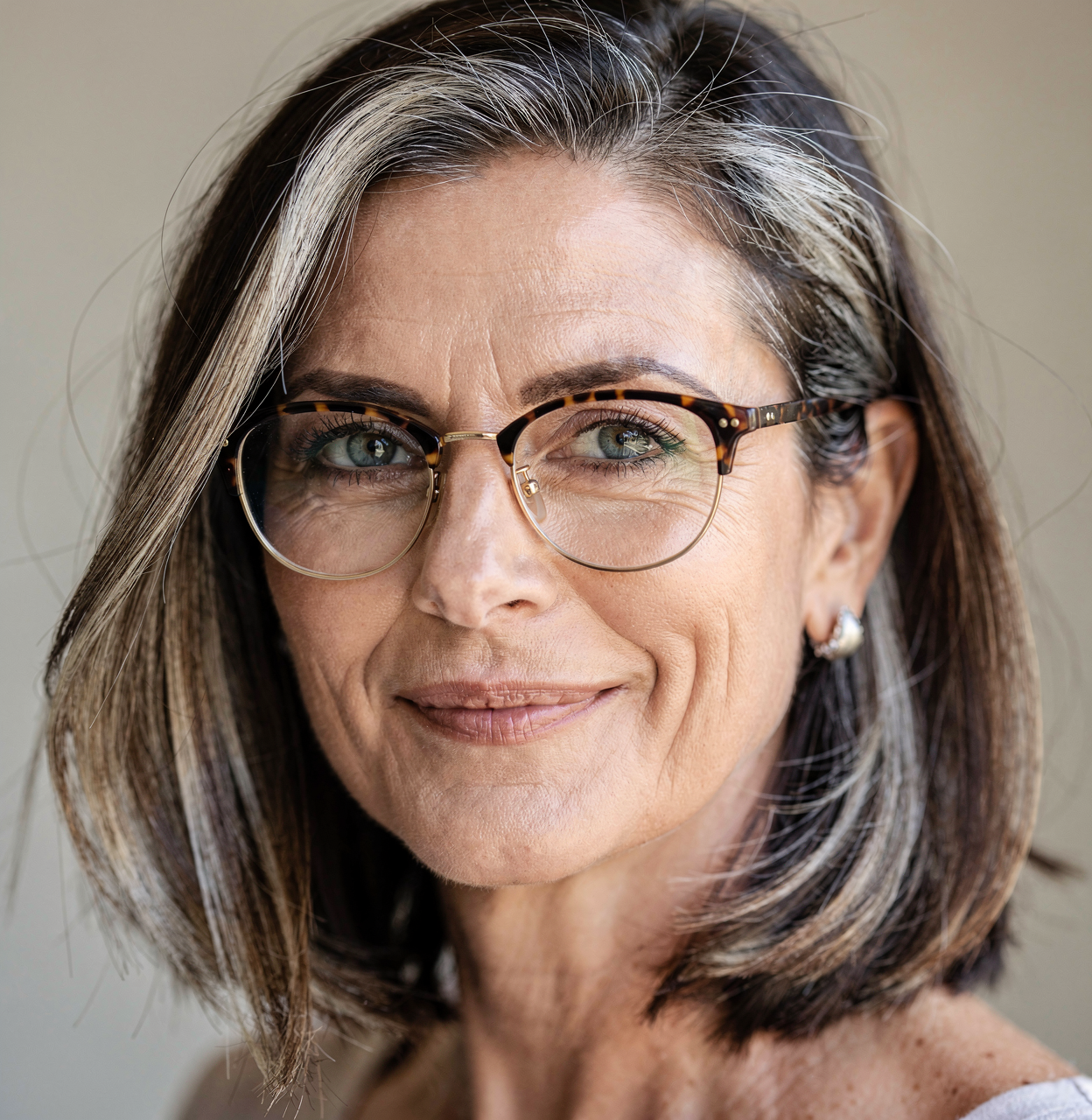 A woman in her late fifties — silver-streaked hair, tortoise-shell glasses — looking calmly into the camera.